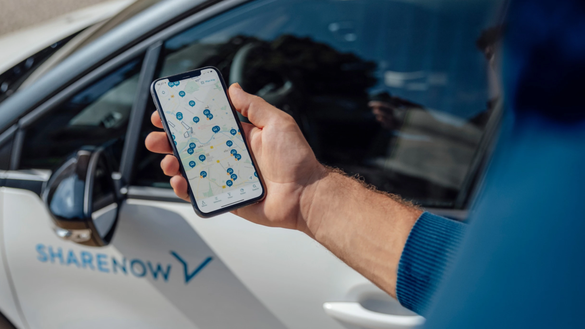 Person looking at Share Now app next to a car